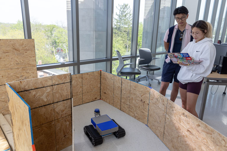 Two students working together using their laptop to drive their robot through an obstacle course