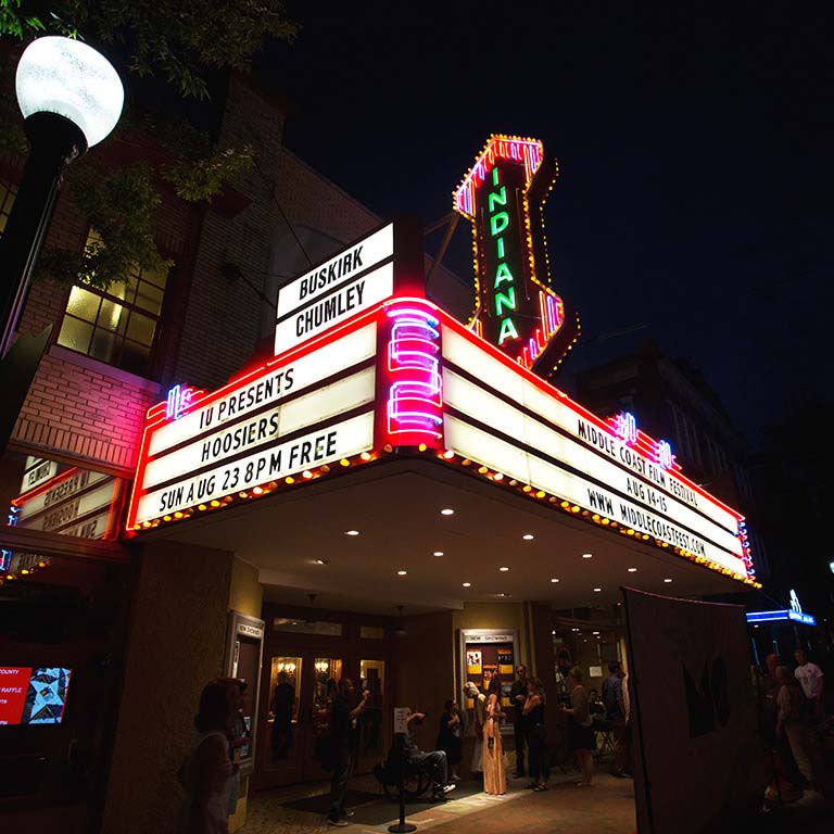 People stand outside the Buskirk-Chumley Theater at night.