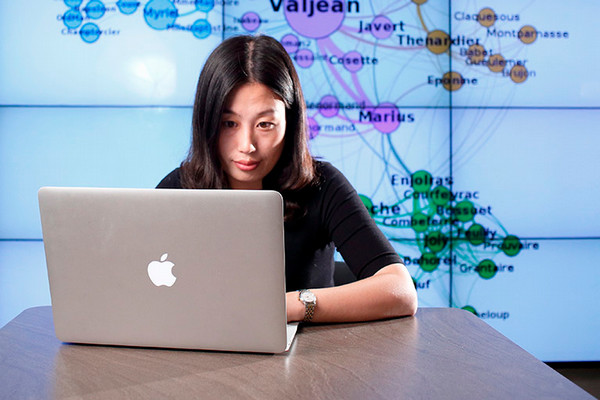 a girl sitting at a table looking at her laptop
