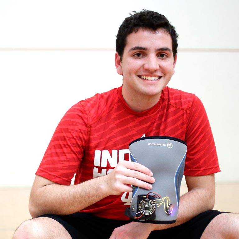 Student Shayan Khokhar holds a knee-brace-based fitness tracker.