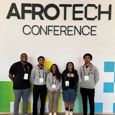 a group of 3 men and 2 women standing in front of the 2024 AfroTech Conference banner.