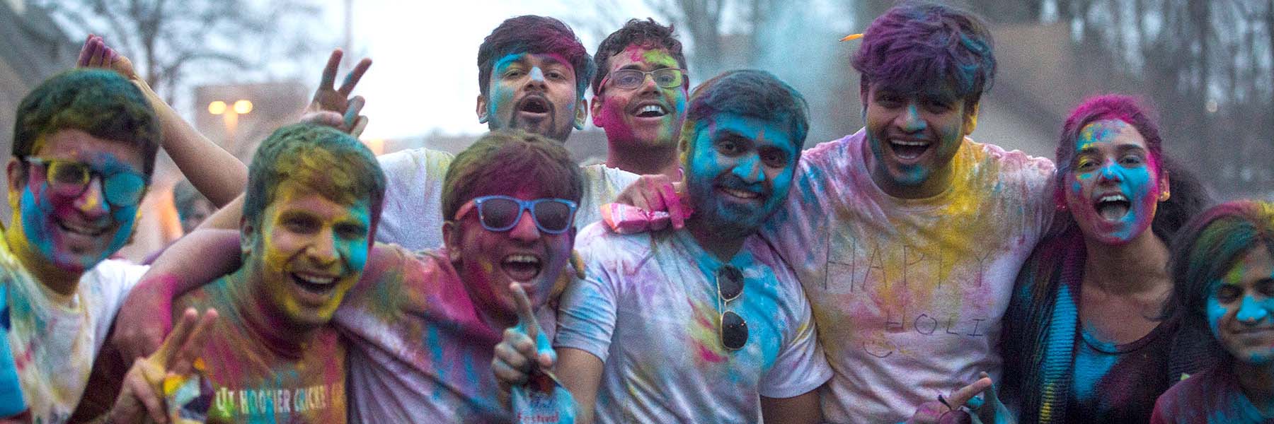 A group of students covered in differently colored powders at Holi Fest.