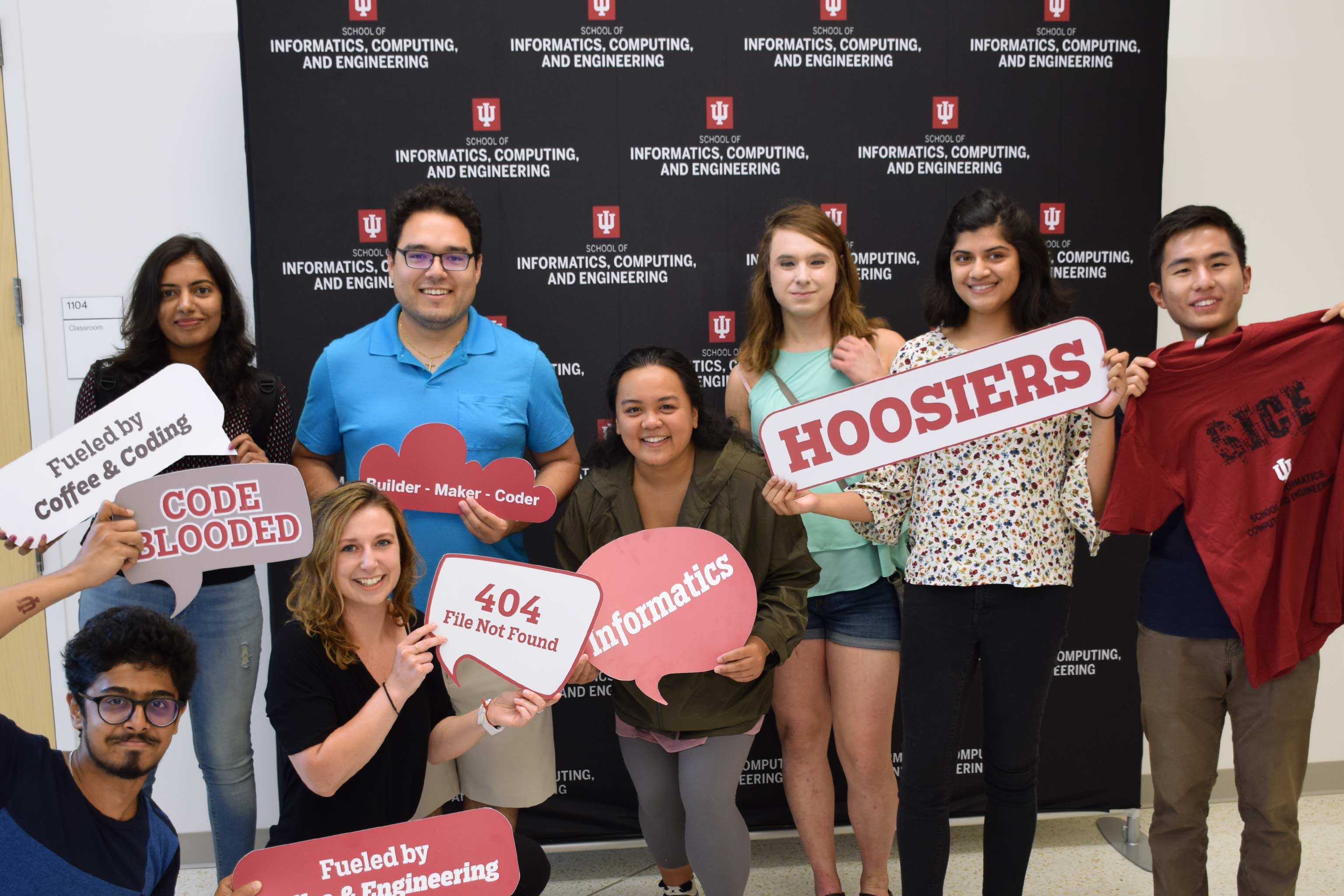 A group of students poses with IU and SICE-related signs.