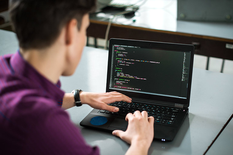 A Serve IT student member writes in a programming language on his laptop.